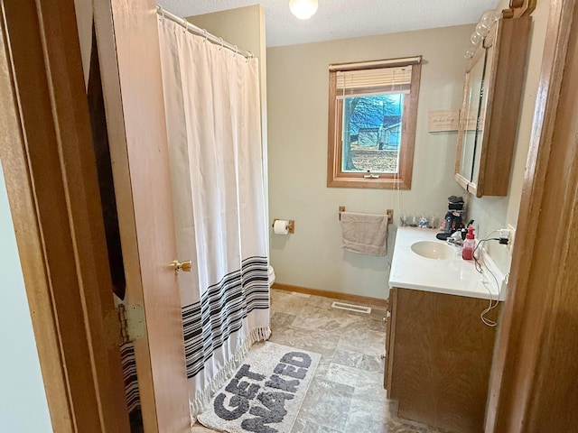 bathroom with visible vents, baseboards, a shower with shower curtain, a textured ceiling, and vanity