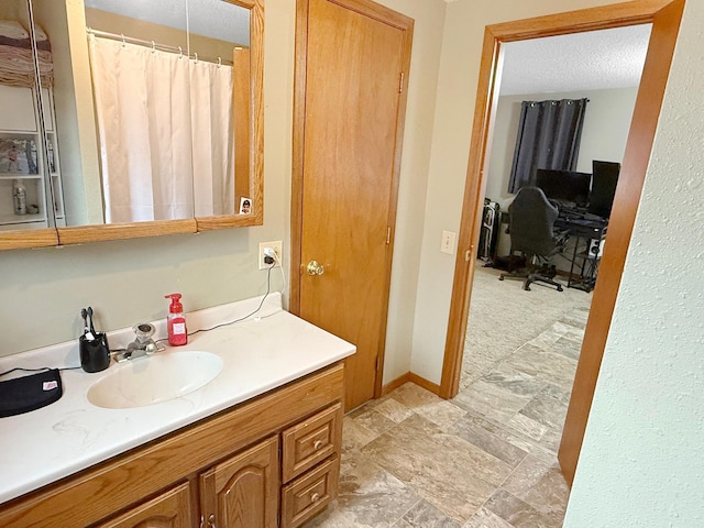 bathroom featuring baseboards, a textured ceiling, and vanity