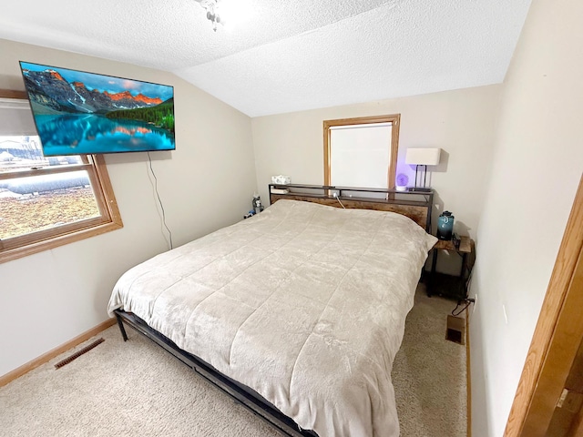 carpeted bedroom featuring lofted ceiling, visible vents, baseboards, and a textured ceiling