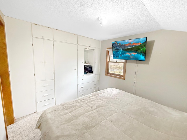 bedroom featuring lofted ceiling, carpet, a closet, and a textured ceiling