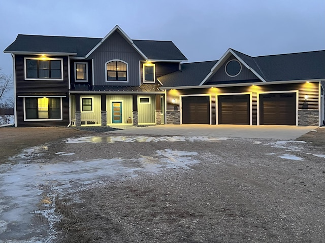 view of front facade featuring board and batten siding, an attached garage, stone siding, and driveway