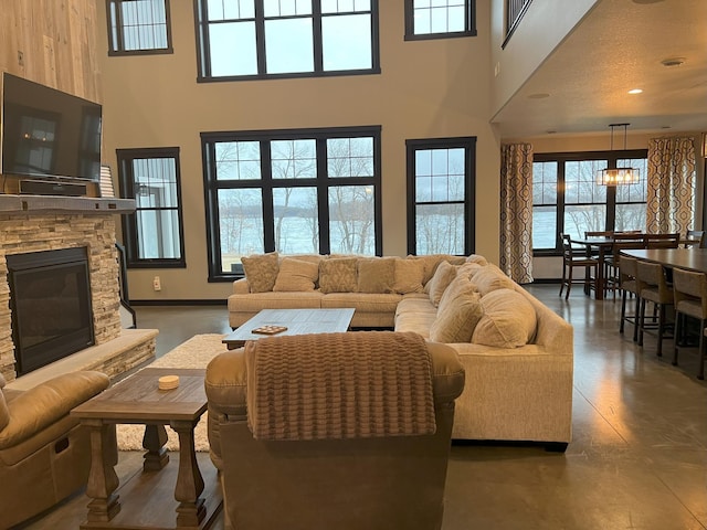 living room with a wealth of natural light, a towering ceiling, and a fireplace