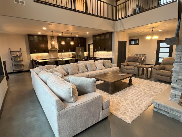 living room with visible vents, baseboards, a notable chandelier, and finished concrete floors