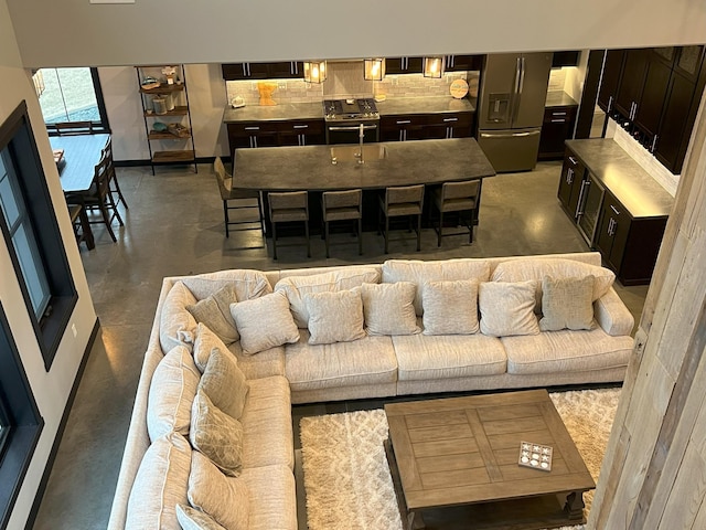 living area with baseboards and finished concrete flooring