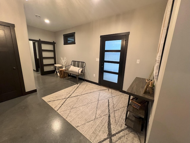 entryway featuring baseboards, concrete flooring, and a barn door