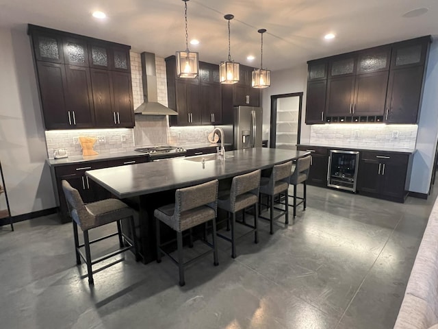 kitchen featuring a sink, wine cooler, appliances with stainless steel finishes, a kitchen breakfast bar, and wall chimney exhaust hood