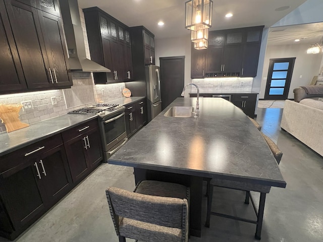 kitchen with a sink, decorative backsplash, stainless steel appliances, glass insert cabinets, and wall chimney range hood