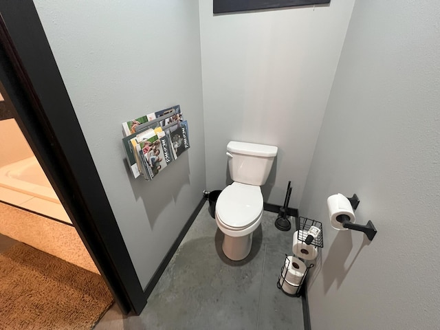 bathroom with baseboards, toilet, and concrete flooring