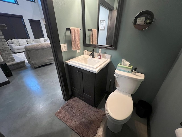 half bath with toilet, concrete flooring, and vanity