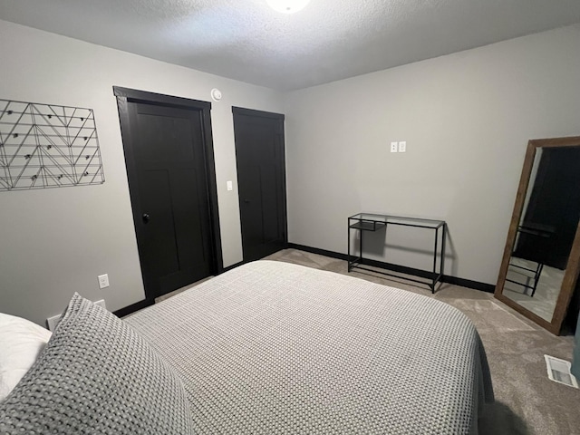 bedroom with light carpet, visible vents, a textured ceiling, and baseboards