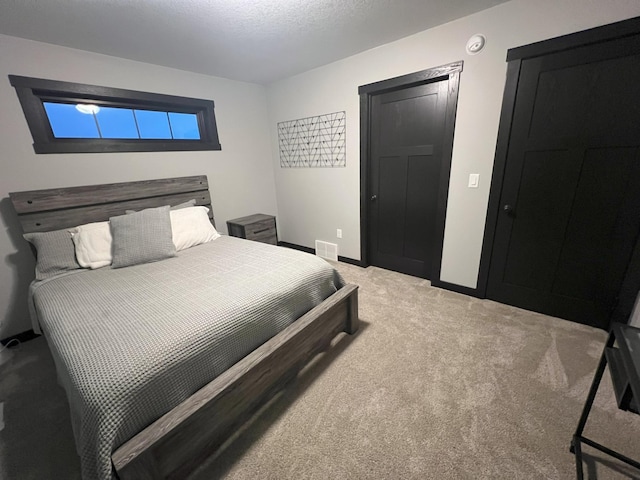 bedroom featuring a textured ceiling, baseboards, visible vents, and light carpet