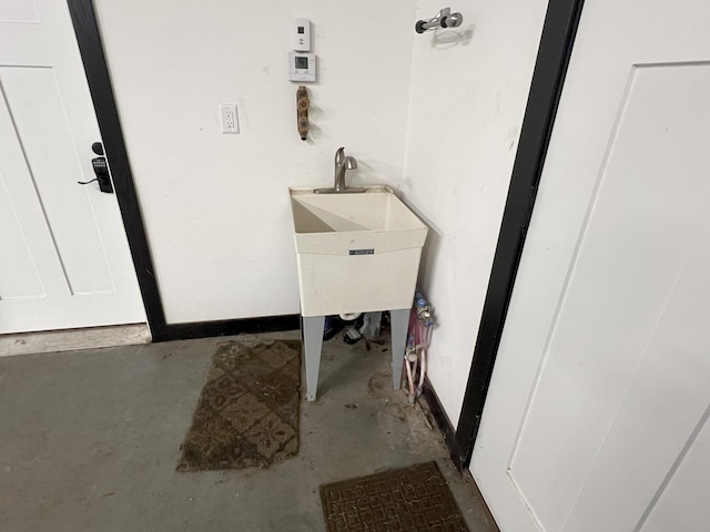 interior space featuring baseboards, concrete flooring, and a sink