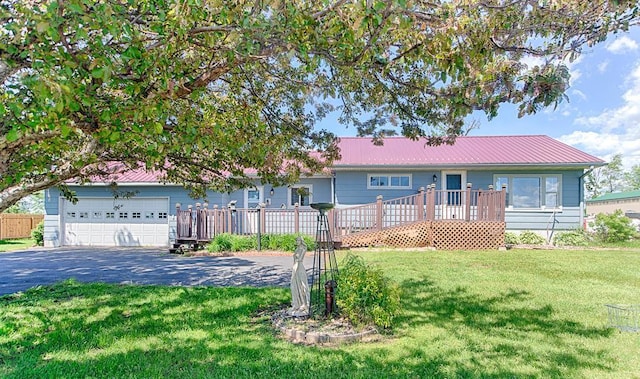 ranch-style home with metal roof, a garage, a front lawn, and aphalt driveway