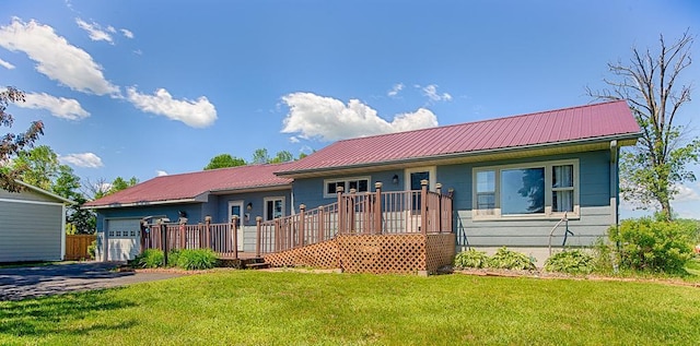 ranch-style home featuring a garage, metal roof, a front yard, and a deck