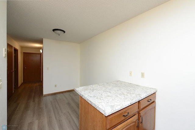 kitchen with baseboards, brown cabinets, light countertops, a textured ceiling, and light wood-type flooring