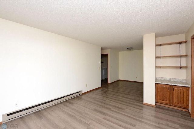 unfurnished room with light wood finished floors, baseboards, a baseboard heating unit, and a textured ceiling