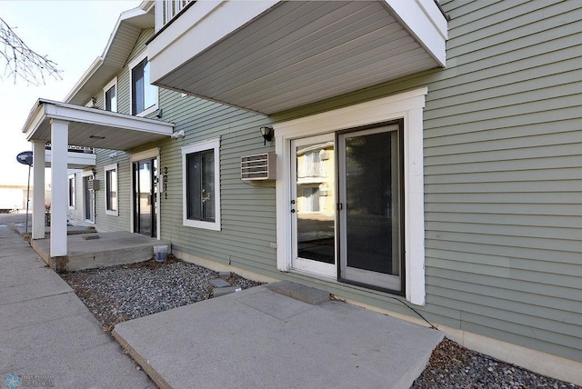 doorway to property with a wall mounted air conditioner and a patio