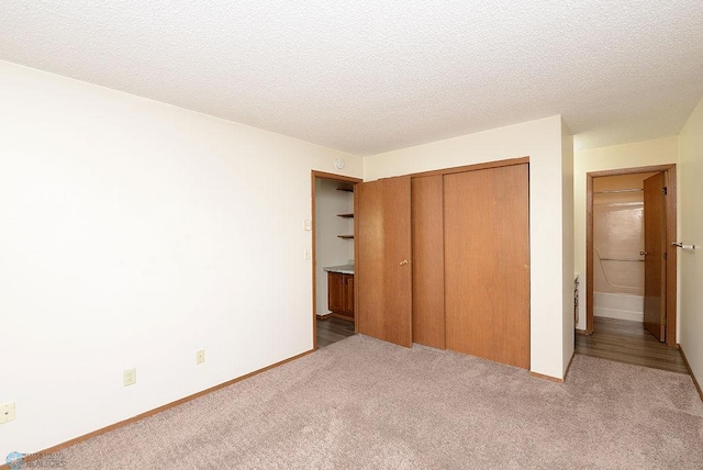 unfurnished bedroom featuring a textured ceiling, a closet, carpet, and baseboards