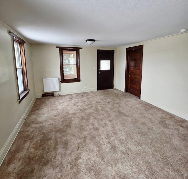 unfurnished room featuring radiator heating unit, carpet flooring, and baseboards