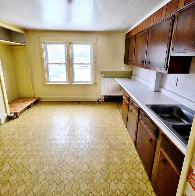 kitchen featuring a sink, baseboards, light countertops, light floors, and radiator heating unit