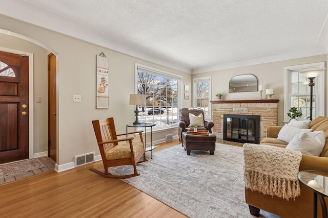 interior space featuring visible vents, a fireplace, light wood-style floors, arched walkways, and a textured ceiling