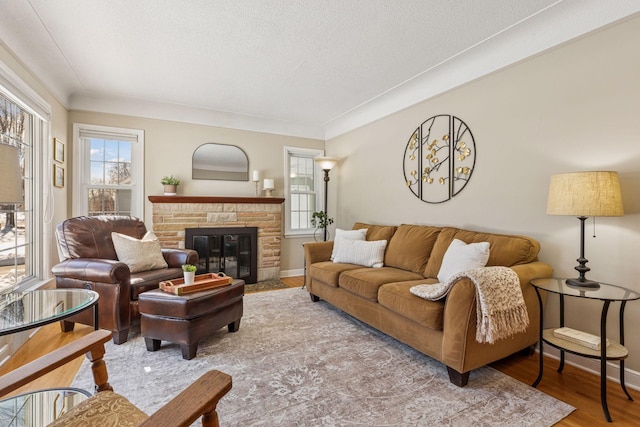 living room featuring baseboards, a textured ceiling, wood finished floors, and a fireplace