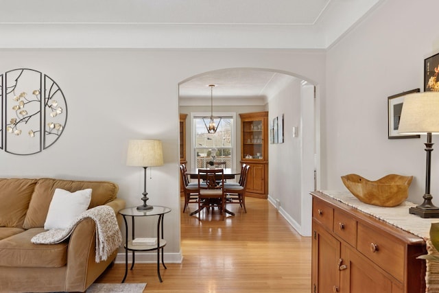 living room featuring baseboards, arched walkways, and light wood-style floors