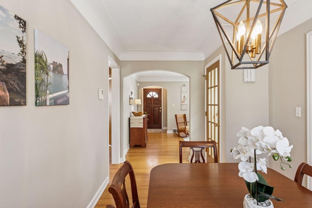 dining room with baseboards, arched walkways, a notable chandelier, and light wood finished floors