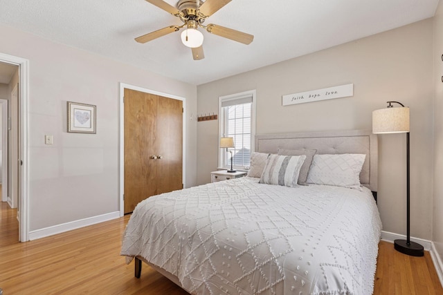 bedroom with a closet, ceiling fan, baseboards, and light wood-style floors