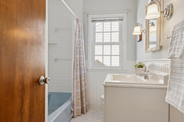 full bath featuring plenty of natural light, wainscoting, vanity, and shower / tub combo