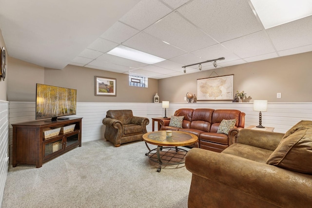 carpeted living room with rail lighting, a drop ceiling, and wainscoting