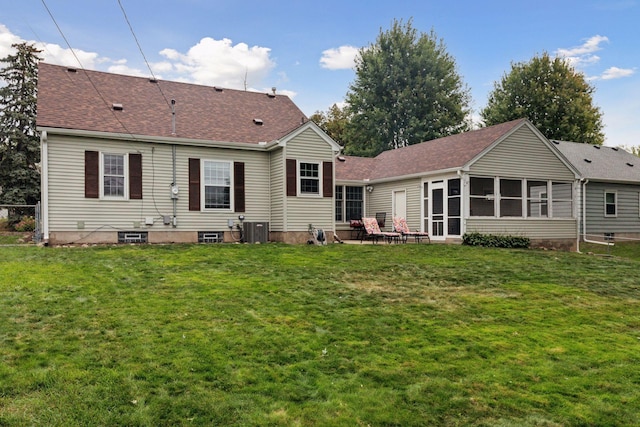 rear view of house featuring central air condition unit, a yard, a sunroom, and a shingled roof