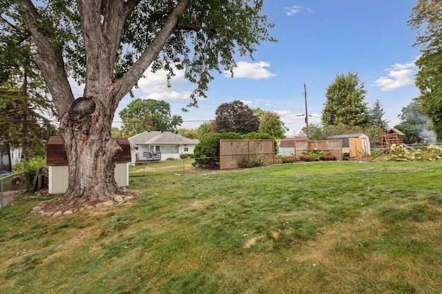 view of yard featuring an outbuilding, fence, and a shed