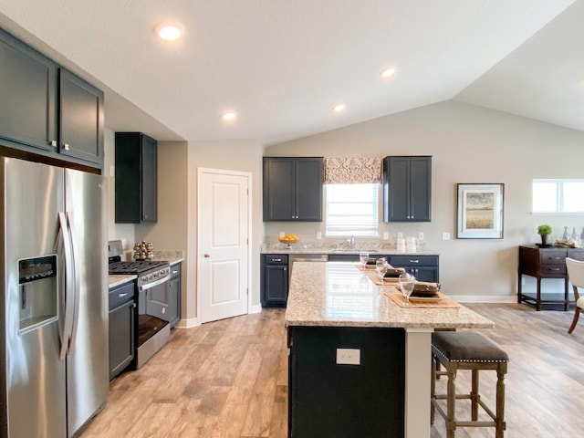 kitchen featuring stainless steel appliances, a healthy amount of sunlight, a kitchen bar, and a center island