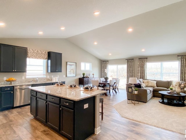 kitchen featuring light wood finished floors, open floor plan, a center island, a healthy amount of sunlight, and stainless steel dishwasher