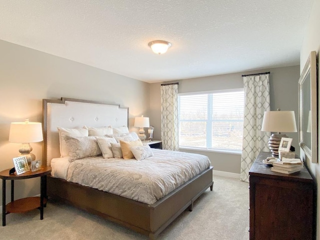 bedroom with light carpet, a textured ceiling, and baseboards