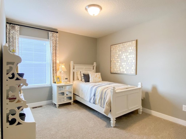 bedroom featuring baseboards, visible vents, a textured ceiling, and carpet flooring