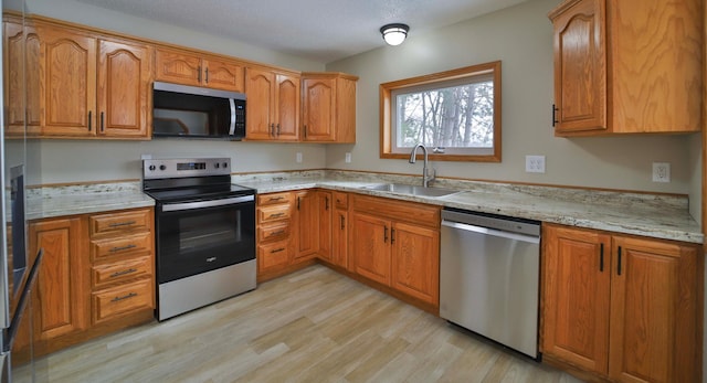 kitchen featuring brown cabinetry, appliances with stainless steel finishes, and a sink