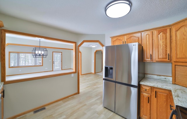 kitchen with visible vents, a textured ceiling, arched walkways, stainless steel fridge with ice dispenser, and light wood finished floors