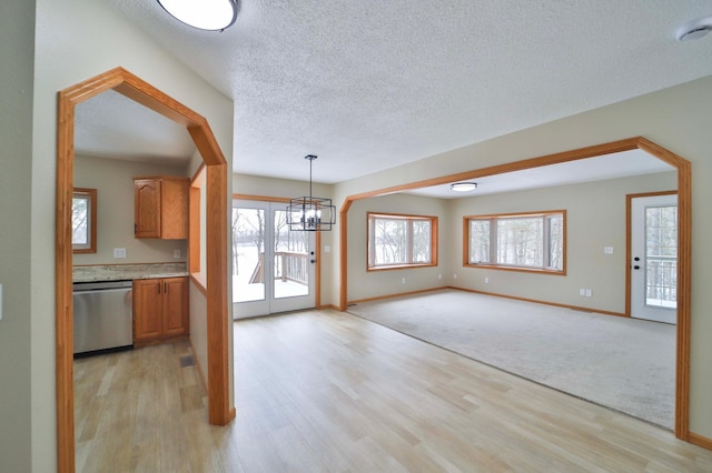 kitchen featuring light wood-type flooring, plenty of natural light, dishwasher, and light countertops