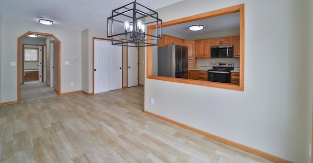 kitchen featuring electric stove, stainless steel microwave, black fridge with ice dispenser, arched walkways, and light wood finished floors