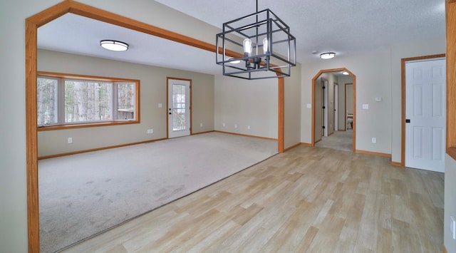 interior space with wood finished floors, baseboards, arched walkways, and a textured ceiling