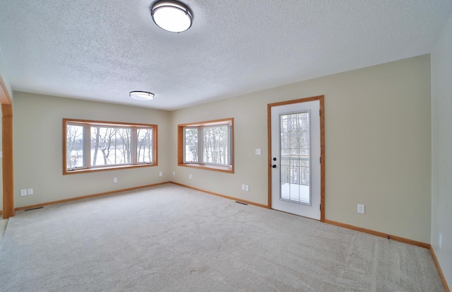 unfurnished room with visible vents, carpet, baseboards, and a textured ceiling