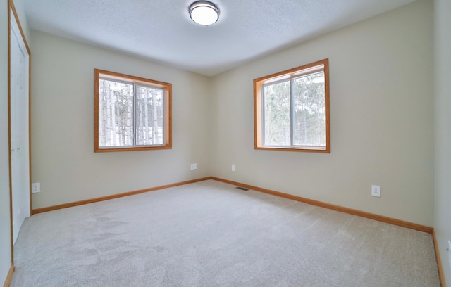 unfurnished bedroom featuring baseboards, multiple windows, carpet, and visible vents