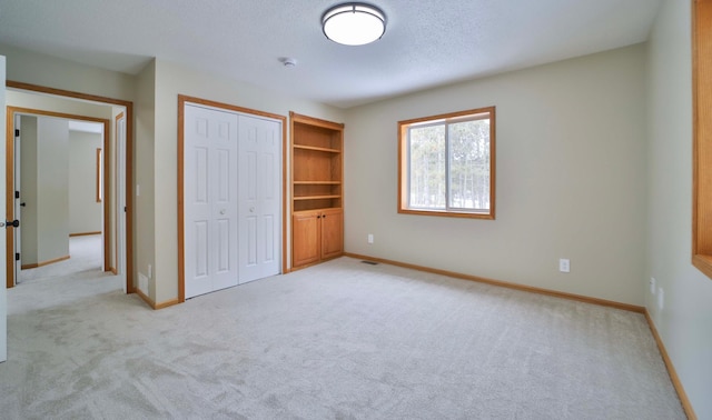 unfurnished bedroom with visible vents, baseboards, light carpet, a closet, and a textured ceiling