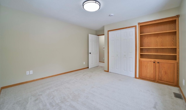 unfurnished bedroom with visible vents, baseboards, a closet, and light carpet