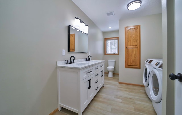 full bath with wood finished floors, baseboards, a sink, toilet, and washing machine and dryer