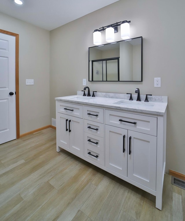 full bathroom featuring visible vents, a shower stall, wood finished floors, and a sink