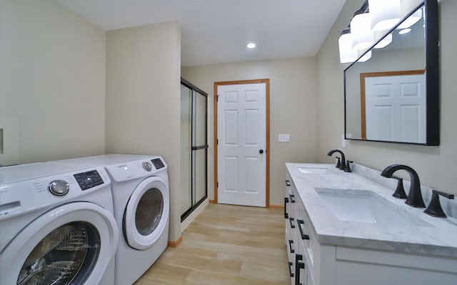 laundry room featuring a sink, light wood-style flooring, cabinet space, and washing machine and dryer