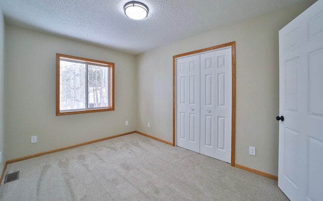 unfurnished bedroom featuring carpet, visible vents, baseboards, a closet, and a textured ceiling